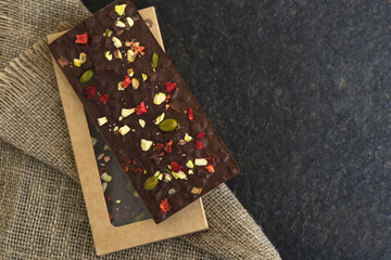 Chocolate bars handmade with strawberries and pistachios on a black background. Craft vegan...