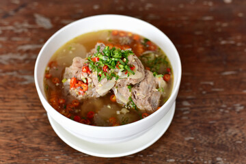 Leng boiled chilli bone food Delious. Thai food call “Leng” is boiled pork bones with spicy chili. In a white bowl, place it on a wooden table