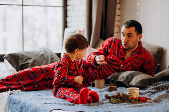 Happy Family Getting Ready For Christmas. Father And Little Son In Red Plaid Pajamas At Home.