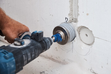 Builder with hummer drill perforator drills hole in a wall