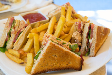 A club sandwich (clubhouse sandwich) is a sandwich of toasted bread, sliced cooked chicken or turkey, ham or fried bacon, lettuce, tomato, and mayonnaise. It is served with french fries.
