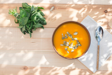 Pumpkin soup with seeds in a dark clay plate in the yard. Healthy food concept. Healthy lifestyle concept