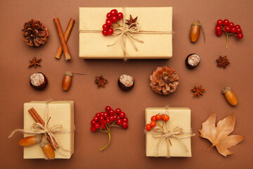 Autumn composition and gifts on brown background. Pattern made of autumn leaves, acorn, pine cones.