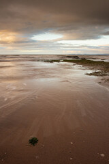 Sunrise over sandy beach with incoming tide