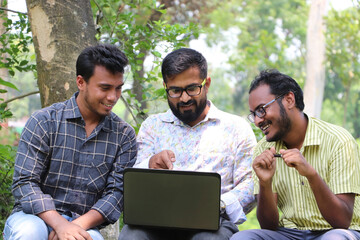 Two Asian students discussing an academic topic with their mentor outside on the university campus...
