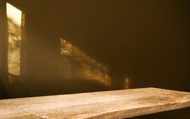 the dark background of the wall on the glare of the glare falling from the window and the shabby old wooden table. Empty space for product installation.