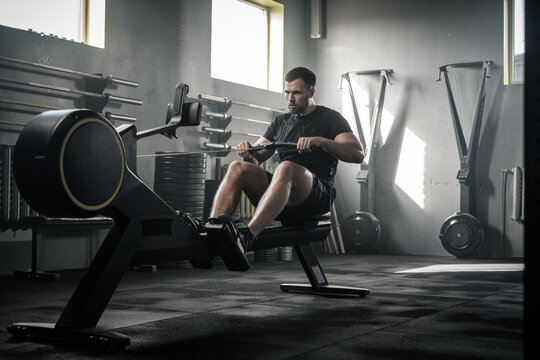 Athletic Male Do Hard Exercises With Rowing Machine .