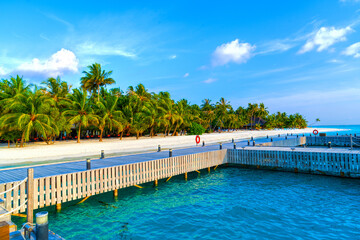 Wooden bridges leading to the huts on the shores of the tropical, warm sea. Maldives. Tourism concept.