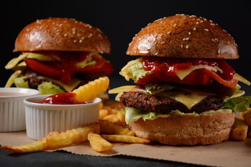 Homemade burger with grilled beef, cheese, onion, tomato, and green salad, sauce, with pickles and French fries