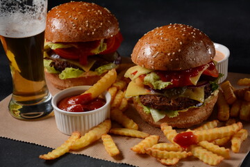 Homemade burger with grilled beef, cheese, onion, tomato, and green salad, sauce, with pickles and French fries
