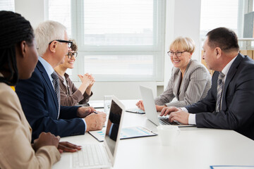 International group of business people working and communicating sitting near office desk.