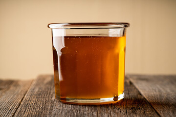 Jar with freshly harvested liquid honey on the old wooden table. Selective focus.