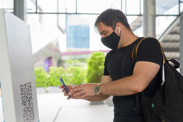 Portrait of Persian man with mask scanning QR code to register entry