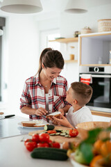 Mother making breakfast with sons. Young family preparing delicious food in kitchen.