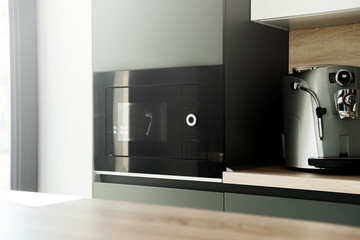 A modern and black oven near a coffee machine in the kitchen