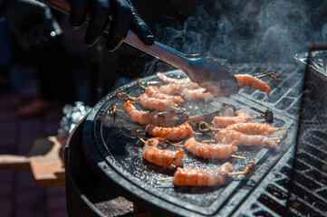 A professional cook prepares shrimps on the grill outdoor, food or catering concept