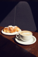 Cappuccino with latte art and croissant at the cafe