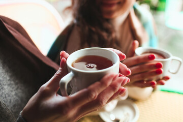 Mature mother and her young daughter sit together in cafe or restaurant. Close up picture of two...