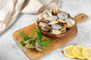Boiled clams in a wooden bowl on a light gray table. Shellfish close-up. Seafood dish
