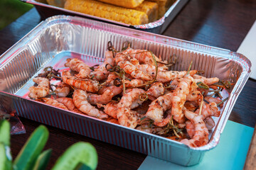 A professional cook prepares shrimps on the grill outdoor, food or catering concept