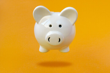 White Piggy bank levitating over a yellow background