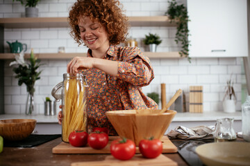 Young woman in kitchen. Beautiful woman making pasta
