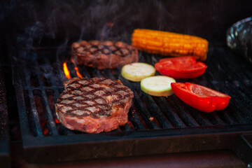 Beef steaks with vegetables on the grill with flames