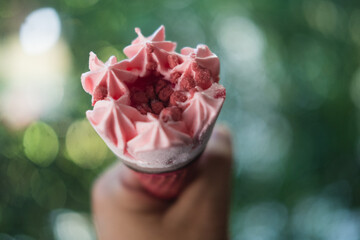 Hand holding pink waffle cone with strawberry ice cream