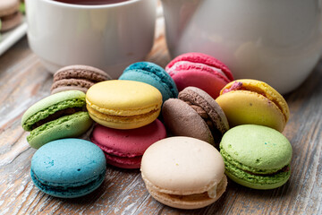 Lots of different macarons on wooden table close up
