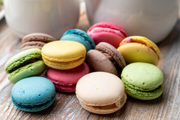 Lots of different macarons on wooden table close up