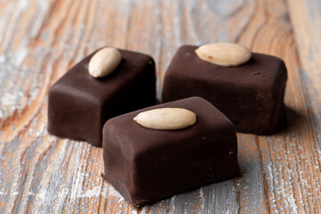 Three small gourmet chocolate candies on wooden background