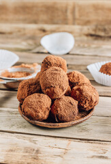 Homemade chocolate truffles candy ball on a plate sprinkled with cocoa on a rustc wooden background.