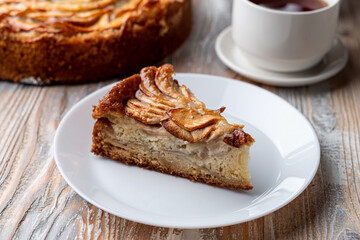 A slice of granny apple pie with cinnamon and caramelized apples on a rustic wooden table
