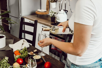 Woman pouring wine in a glass in a kitchen