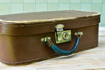 old suitcase lies on a shabby wooden table, half-side view