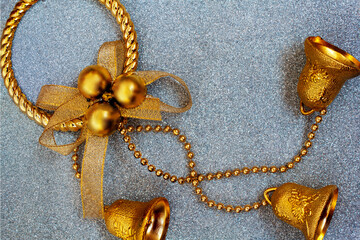 Golden Christmas toy in the form of a wreath with three bells on a silver background with sparkling...