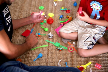 kid playing with toys with his young father in their home living room, home interior