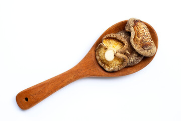 Dried shiitake mushrooms on wooden spoon on white.