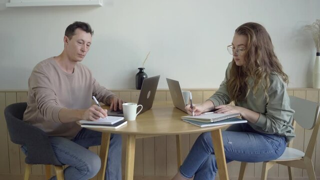 Modern couple working with laptops. Smart young couple discussing project at desk