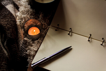 Hygge style. Warm blanket, burning candles, book for notes. vintage style, still life.