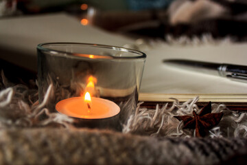Hygge style. Warm blanket, burning candles, book for notes. vintage style, still life.