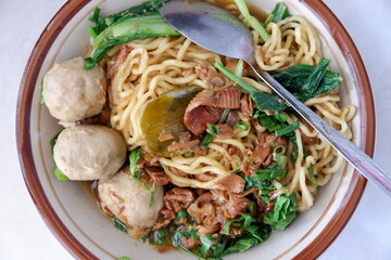 High angle view of chicken noodle meatball (mie ayam bakso) with vegetables in a bowl on white background