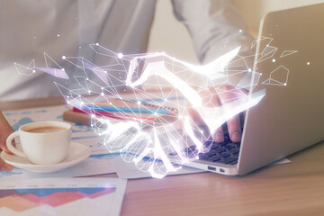 Handshake hologram drawing with businessman working on computer on background. Double exposure.