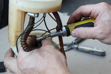 man is independently repairing parts for a car. replacing the gas pump at home with your own