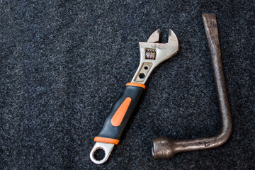 wheel wrenches and adjustable spanners are on a dark gray carpet. car repair concept