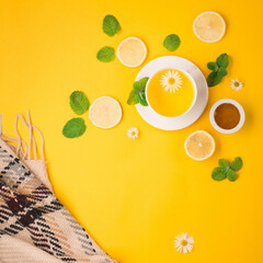 Herbal tea of chamomile flower with mint, ginger, lemon, honey on paper yellow background.