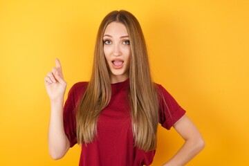 Beautiful Young beautiful caucasian girl wearing red t-shirt over isolated yellow background holding finger up having idea and posing
