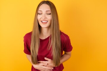 Obraz premium Beautiful Young beautiful caucasian girl wearing red t-shirt over isolated yellow background smiling and laughing hard out loud because funny crazy joke with hands on body.