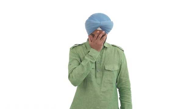 Young frustrated Indian man covering his face by hand expressing disappointment. Isolated on white background