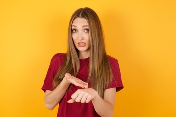 Beautiful Young beautiful caucasian girl wearing red t-shirt over isolated yellow background In hurry pointing to watch time, impatience, upset and angry for deadline delay.
